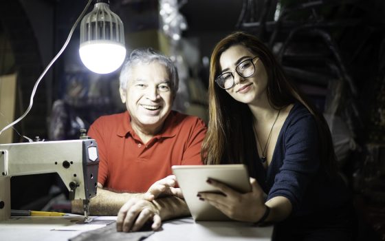 Man and woman in small office with sewing machine and tablet